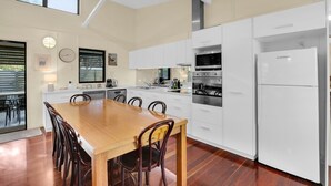 Una cocina moderna con armarios blancos, una mesa de comedor de madera y un horno empotrado.