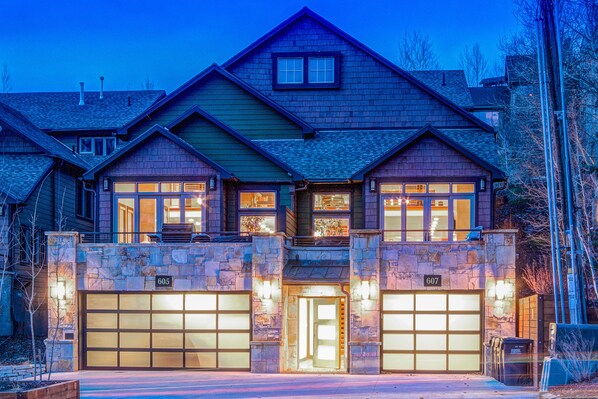 Stunning two-story home with a gabled roof and central chimney, surrounded by a beautifully maintained landscape.