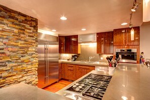 Enjoy cooking in this well-equipped kitchen with a refrigerator, gas range, and wooden cabinetry.