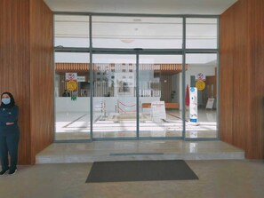 Zona de recepción con puerta de vidrio, mostrador de recepción y un letrero que indica que no se permite fumar.