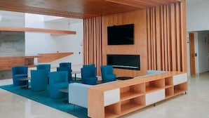 A modern lounge area with a wooden ceiling structure, blue seating, and a flat-screen TV. - Zephyr Agadir (Agadir)