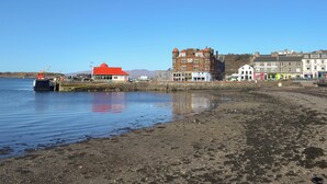 Uma área à beira-mar com um edifício de telhado vermelho, um prédio de tijolos maior com vários andares e vários edifícios menores ao longo da costa.