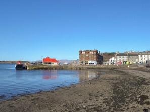 A waterfront area with a red-roofed building, a larger brick building with multiple stories, and several smaller buildings along the shore.