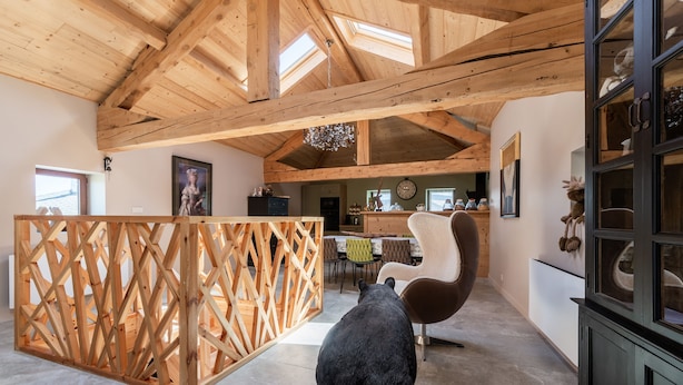 Ein geräumiger Raum mit hoher Decke, Holzbalken, einer Essecke und einer großen Bärenskulptur.