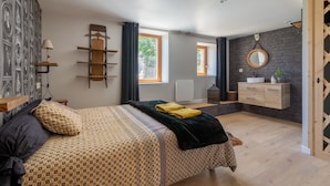 Ein Schlafzimmer mit einem Bett, einem Nachttisch, einem Spiegel, einer Kommode und einem Fenster.