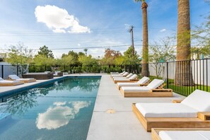 Una piscina al aire libre, sillones reclinables de piscina