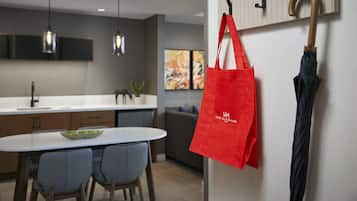 Una cocina moderna con iluminación colgante, un comedor con sillas y un bolso rojo colgado de un gancho.