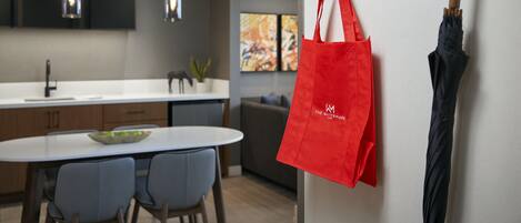 Une cuisine moderne avec des luminaires suspendus, un coin repas avec des chaises et un sac rouge accroché à un crochet.