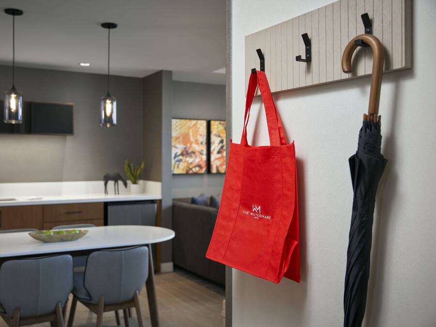 A modern kitchen with pendant lighting, a dining area with chairs, and a red bag hanging on a hook.