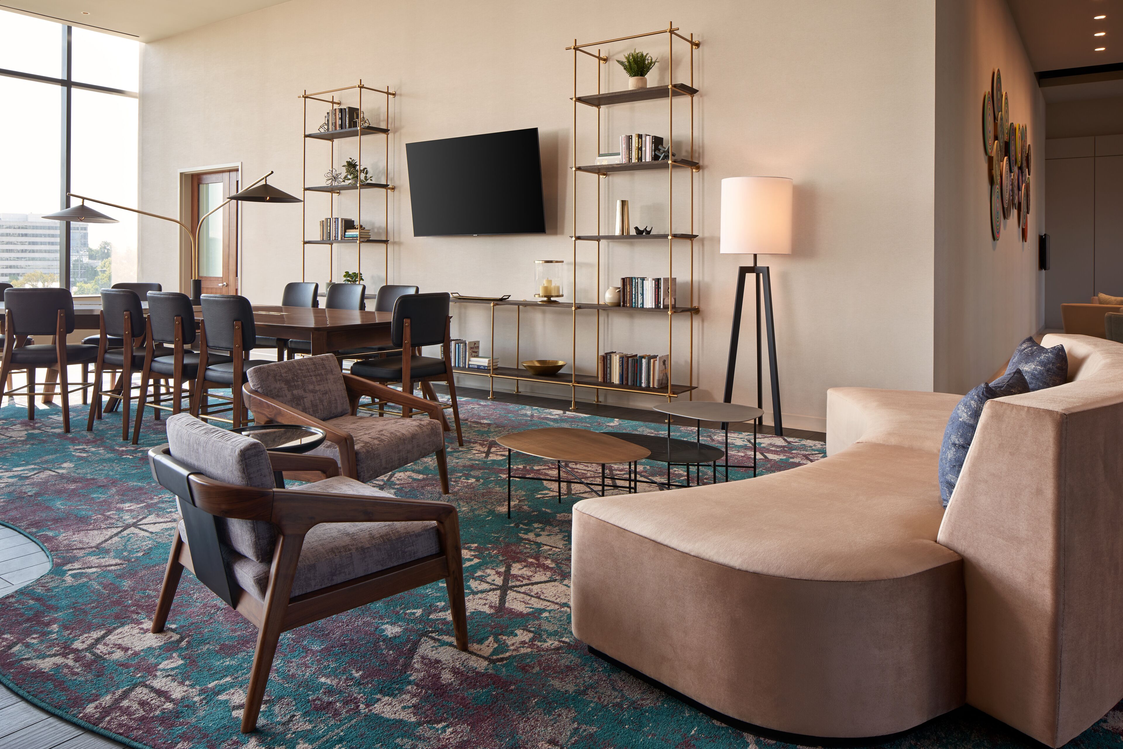 A spacious living area with a large flat-screen TV, a sofa, multiple chairs, a coffee table, and a bookshelf.
