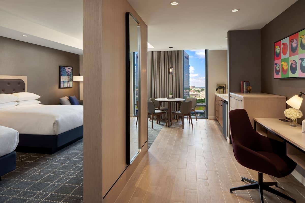 Quarto de hotel com cama, escrivaninha, cadeira e vista para a cidade.