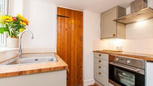 Una cocina con puerta de madera, pileta de acero inoxidable y horno.
