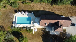 An aerial view of a house with a swimming pool, surrounded by a patio area with umbrellas and lounge chairs. - Mirandole, modern holiday home with views and heated pool (Martel)