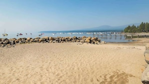 A sandy beach with a rocky breakwater, calm water, and boats. - Steps from Beach-N-Mins to SKI - Updated Interior (Tahoe Vista)