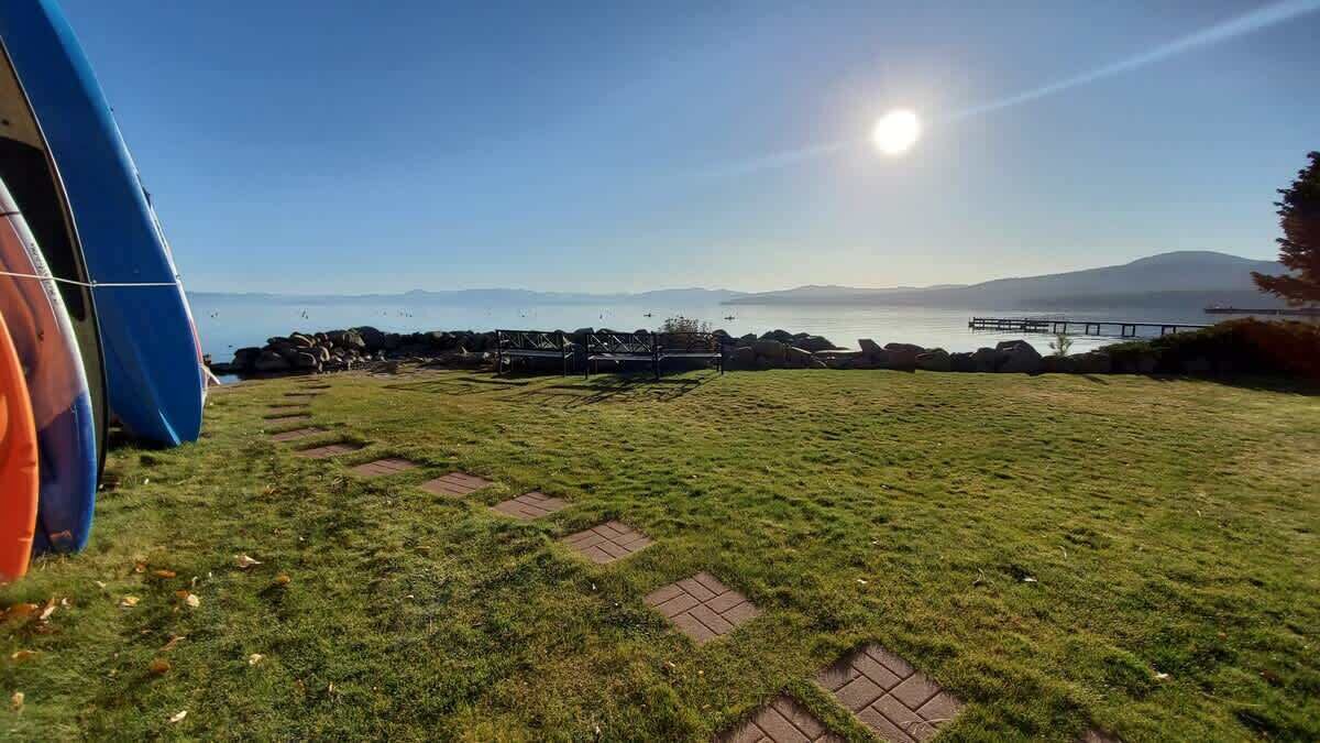 A grassy field with a clear sky, a body of water, and distant mountains.