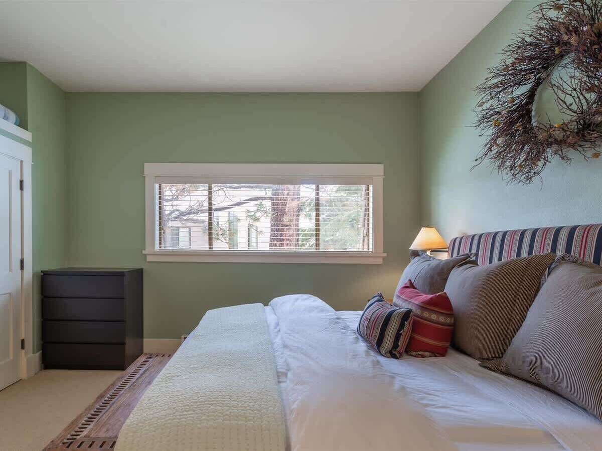 A bedroom with a bed, a window, a dresser, and a lamp.
