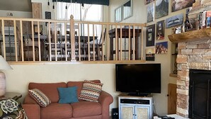 A living room with a sofa, a coffee table, a fireplace, a TV, and a bookshelf. - True ski in-ski out, walk to slopes & town, private hot tub, brand new kitchen (Breckenridge)