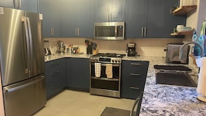A modern kitchen with stainless steel appliances, dark blue cabinets, and a marble countertop. - True ski in-ski out, walk to slopes & town, private hot tub, brand new kitchen (Breckenridge)
