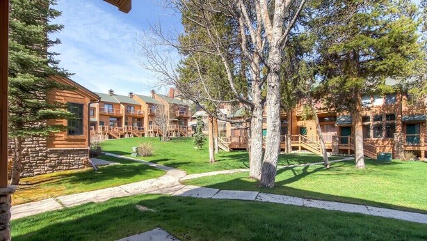 A courtyard with a stone building, wooden deck, and a tree. - True ski in-ski out, walk to slopes & town, private hot tub, brand new kitchen (Breckenridge)