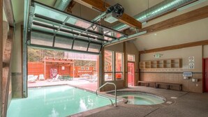 A pool area with two hot tubs, a covered seating area, and a view of a red building outside. - True ski in-ski out, walk to slopes & town, private hot tub, brand new kitchen (Breckenridge)