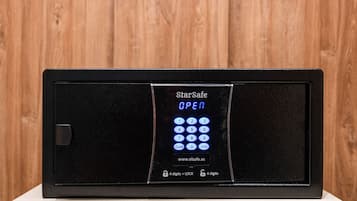 A StarSafe electronic keypad with a digital display indicating 'OPEN' and a website address.
