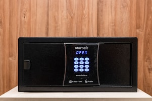 A StarSafe electronic keypad with a digital display indicating 'OPEN' and a website address.