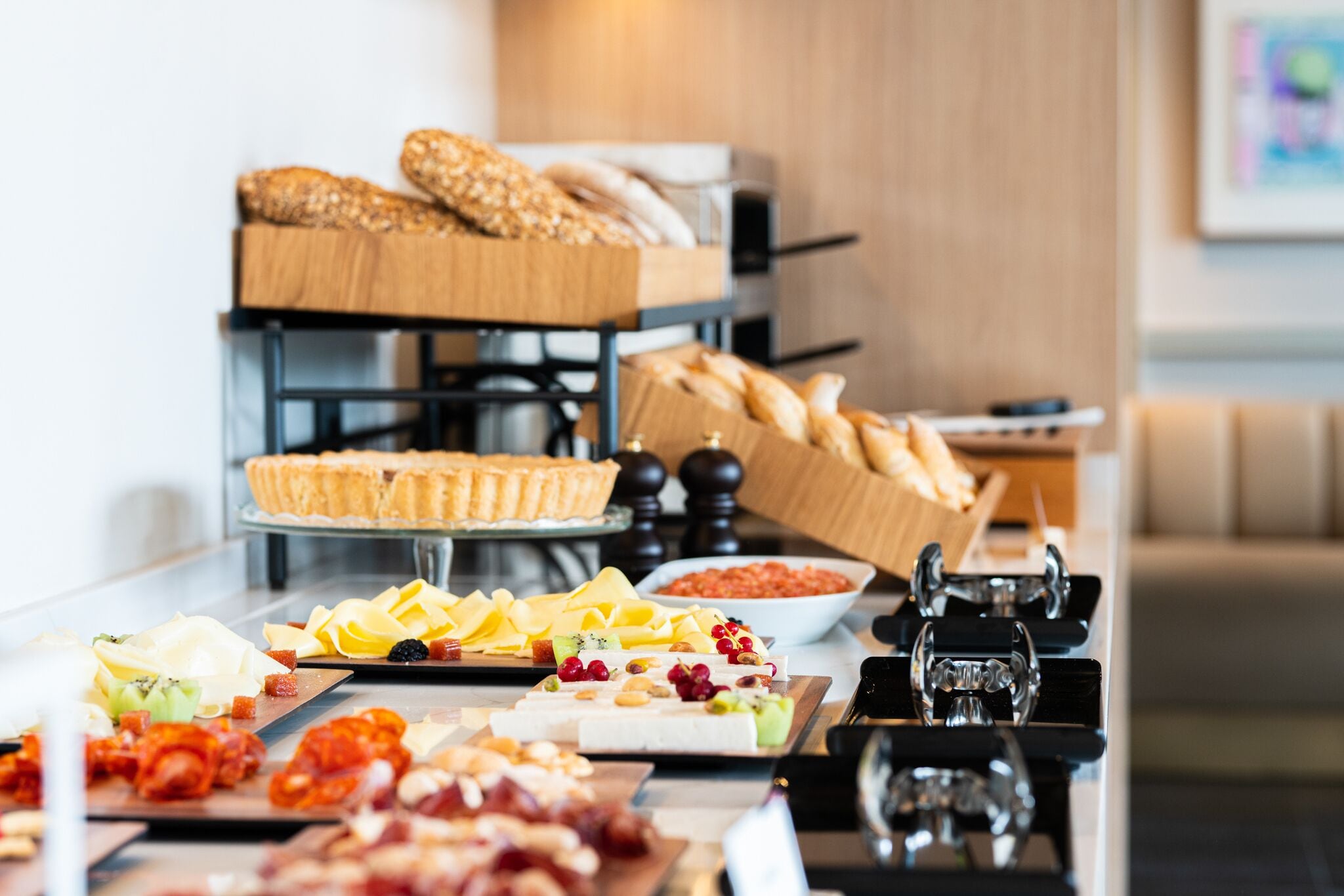 Een buffettafel met verschillende kazen, vleessoorten en broden.