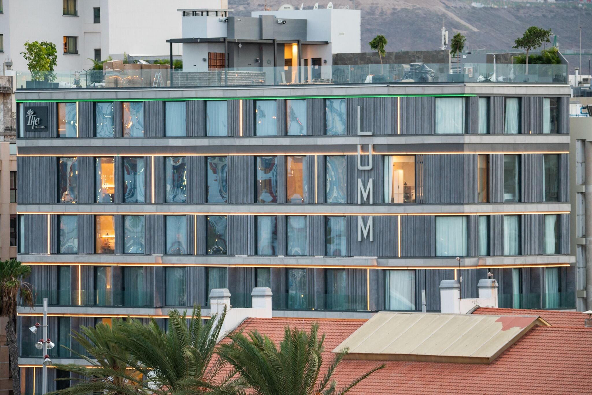 Un hotel modern d'alguns pisos amb un senyal prominent de 'LUMN' a la façana, amb finestres grans i una terrassa a la teulada.