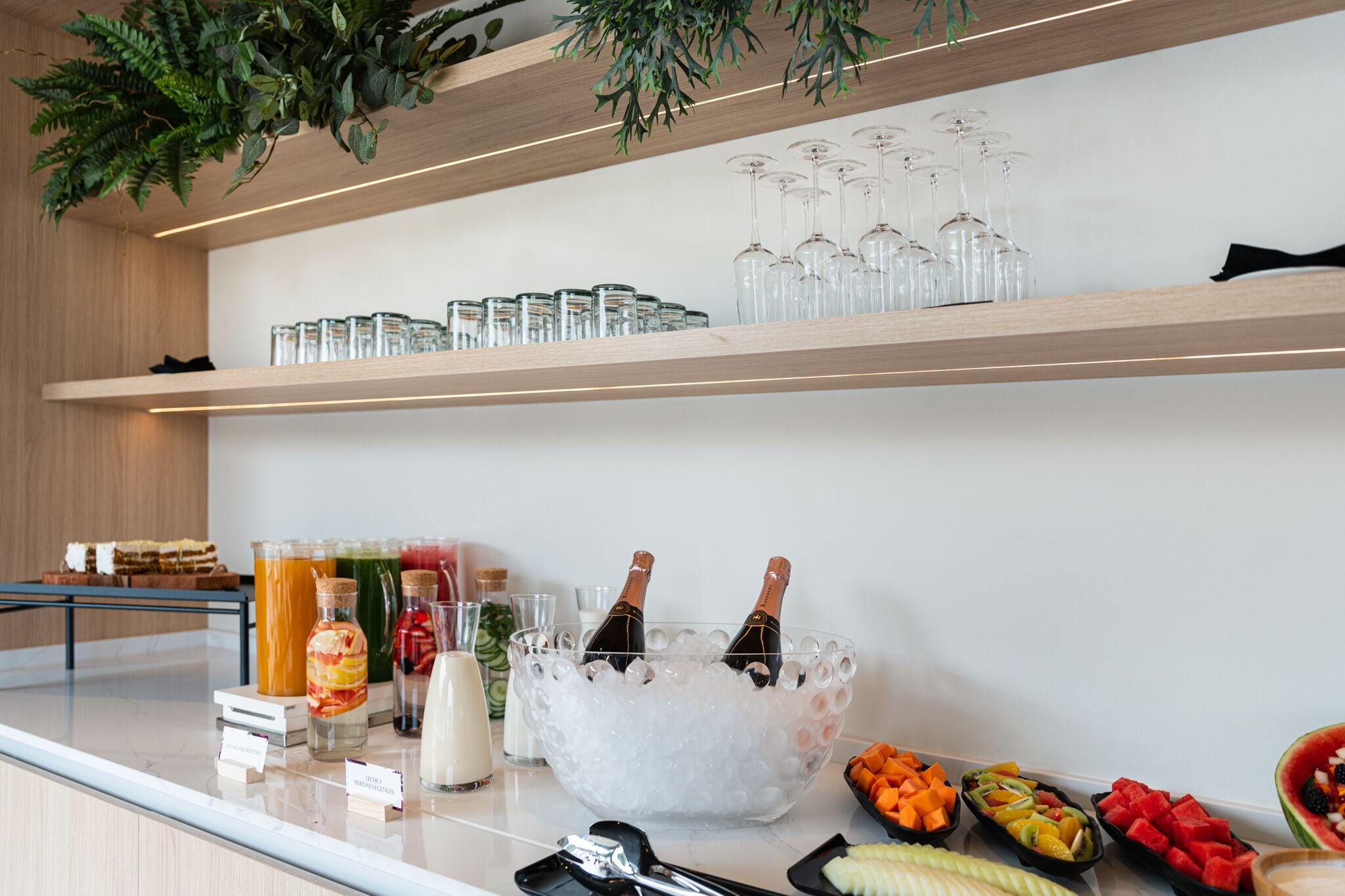Un espace bar proposant une variété de boissons, notamment des bouteilles et des verres, ainsi qu’un récipient rempli de glace contenant des bouteilles de champagne.