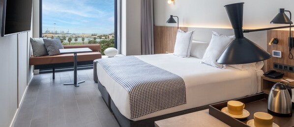 Habitación de hotel moderna con una cama grande, un sofá, un escritorio y vistas a la ciudad.