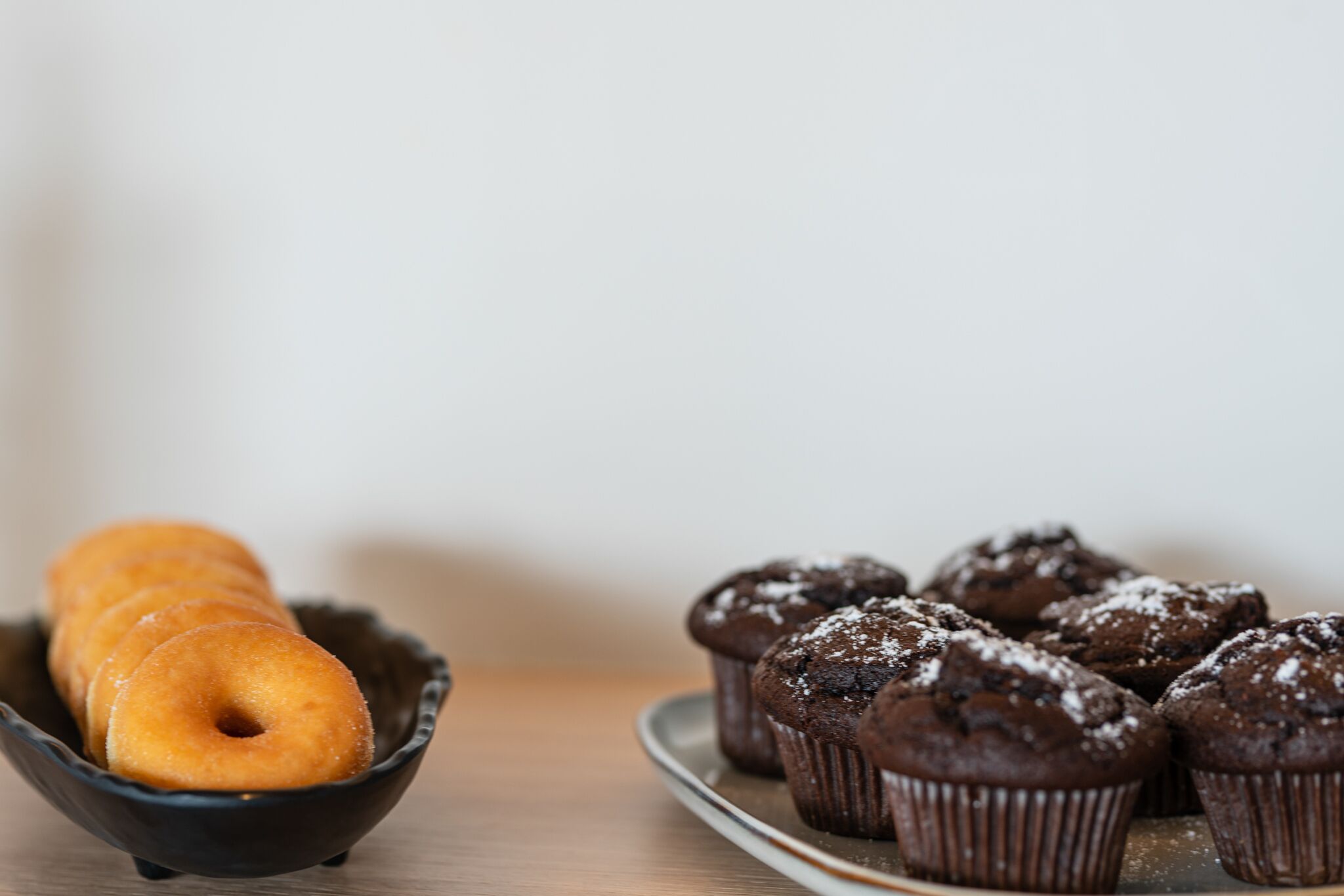 A plate of chocolate muffins and a bowl of donuts.
