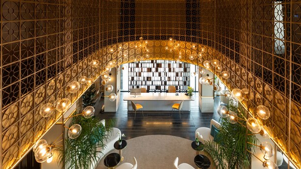 A luxurious lobby with a curved ceiling, a reception desk, and a seating area with plants.