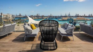 A terrace with wicker chairs and a view of a port and marina.