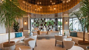 A modern lobby with a central seating area, large potted plants, and a unique ceiling design. - Hotel LIVVO Lumm (Las Palmas de Gran Canaria)