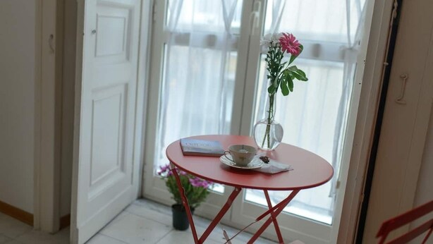 A room with a red table, a book, a cup, and a vase with flowers. - In the heart of Naples (Napoli)
