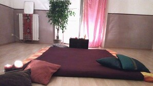 A room with a large, dark-colored rug, wooden flooring, a potted plant, and a radiator. - In the heart of Naples (Napoli)
