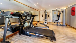 Un gimnasio con cintas de correr, máquinas de pesas y un espejo grande.