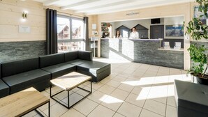 Un moderno vestíbulo de hotel con un mostrador de recepción, zona de estar y vistas al exterior.