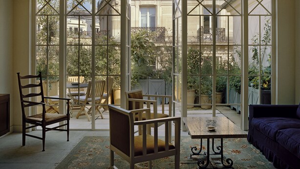 A sunlit room with large windows, a wooden table, two chairs, and a purple sofa. - Hôtel Château Voltaire (Paris)