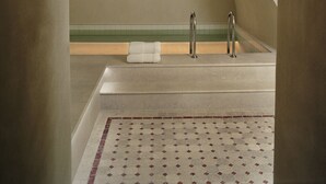 A spa room with a bathtub, a towel, and a wall-mounted light fixture. - Hôtel Château Voltaire (Paris)