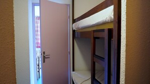 Ein schmaler Flur mit einem Etagenbett und einer Tür zu einem Zimmer mit einem Fenster.