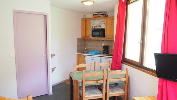 Ein gemütlicher Raum mit einem Bett, einem Esstisch mit Stühlen, einer Küchenzeile und einem Fernseher.