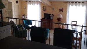 En stue med sofa, stole, fjernsyn og et spiseområde med bord og stole.
