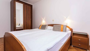 Een slaapkamer met een houten bed, een nachtkastje, een kledingkast en twee wandlampen.