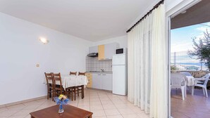 Un espacio habitable compacto con comedor, kitchenette y balcón con mobiliario exterior.