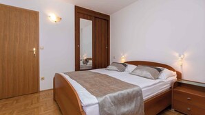 Quarto com cama de madeira, mesa de cabeceira, espelho e duas luminárias na parede.