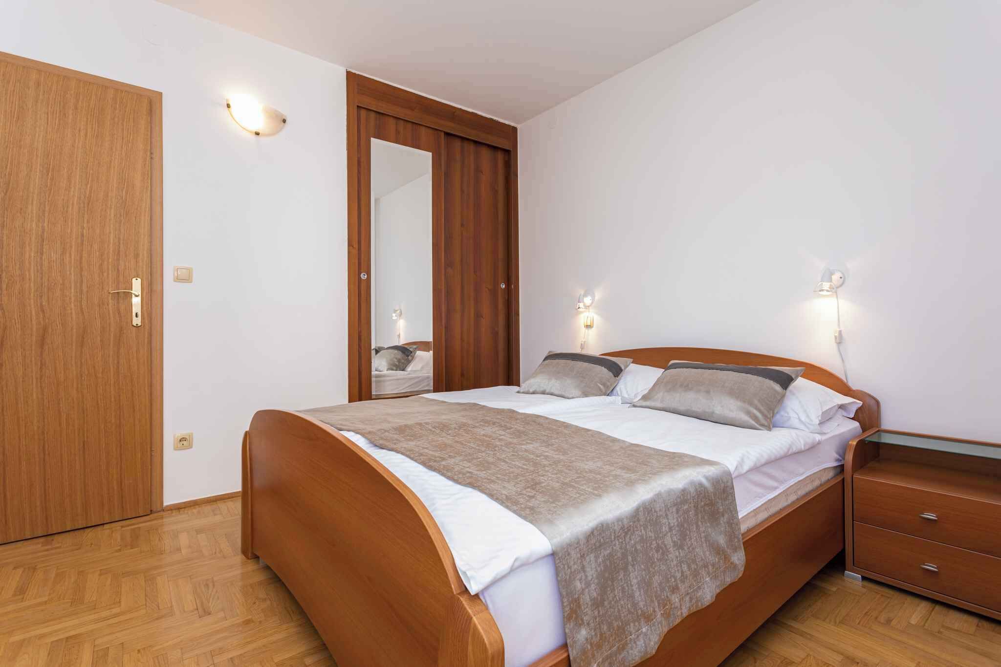 A bedroom with a wooden bed, a nightstand, a mirror, and two wall-mounted lights.