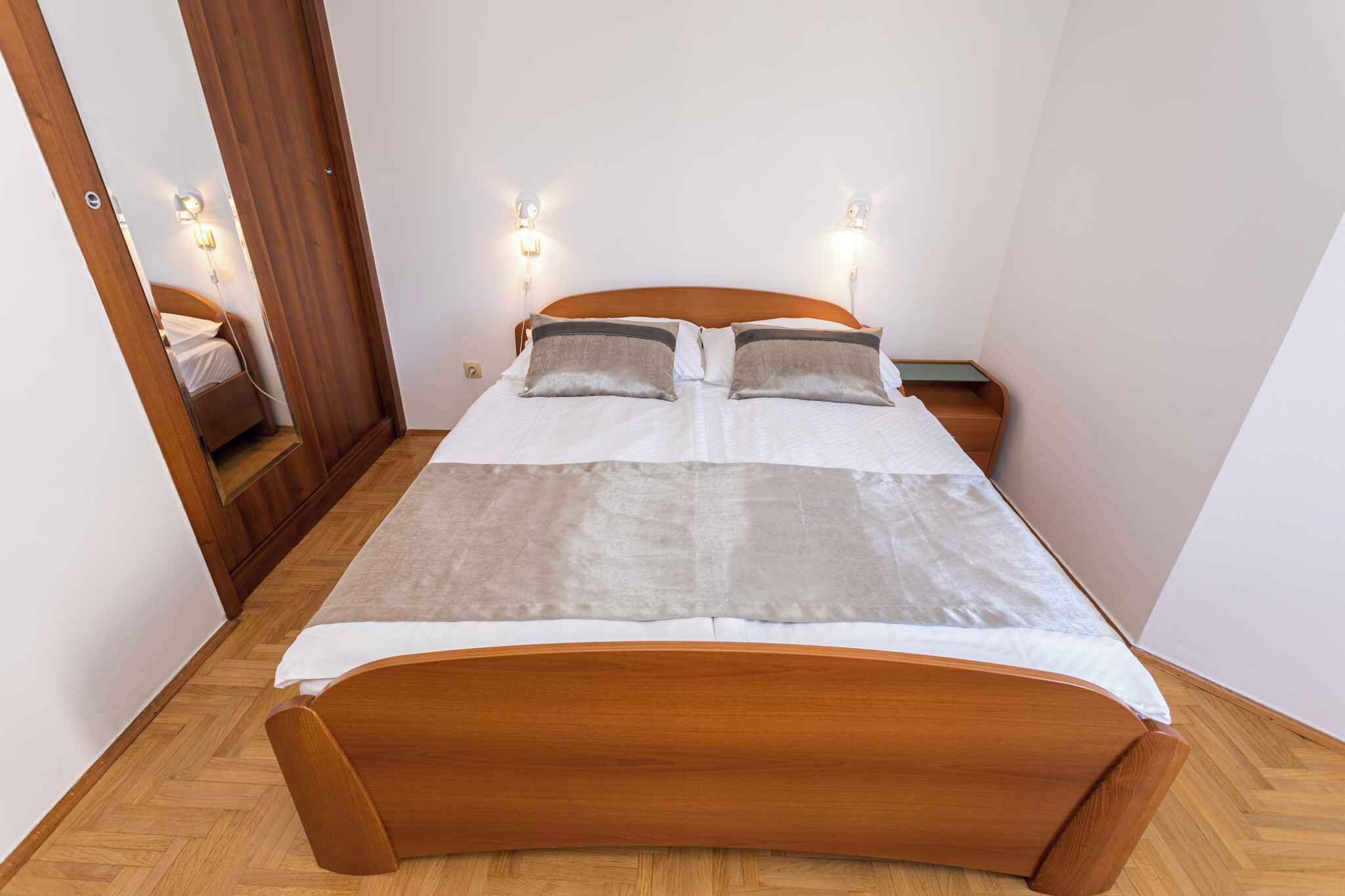 A bedroom with a wooden bed, two bedside lamps, and a mirror on the wall.