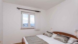 Ein Schlafzimmer mit einem Bett, einem Fenster mit Blick und Holzdielen.