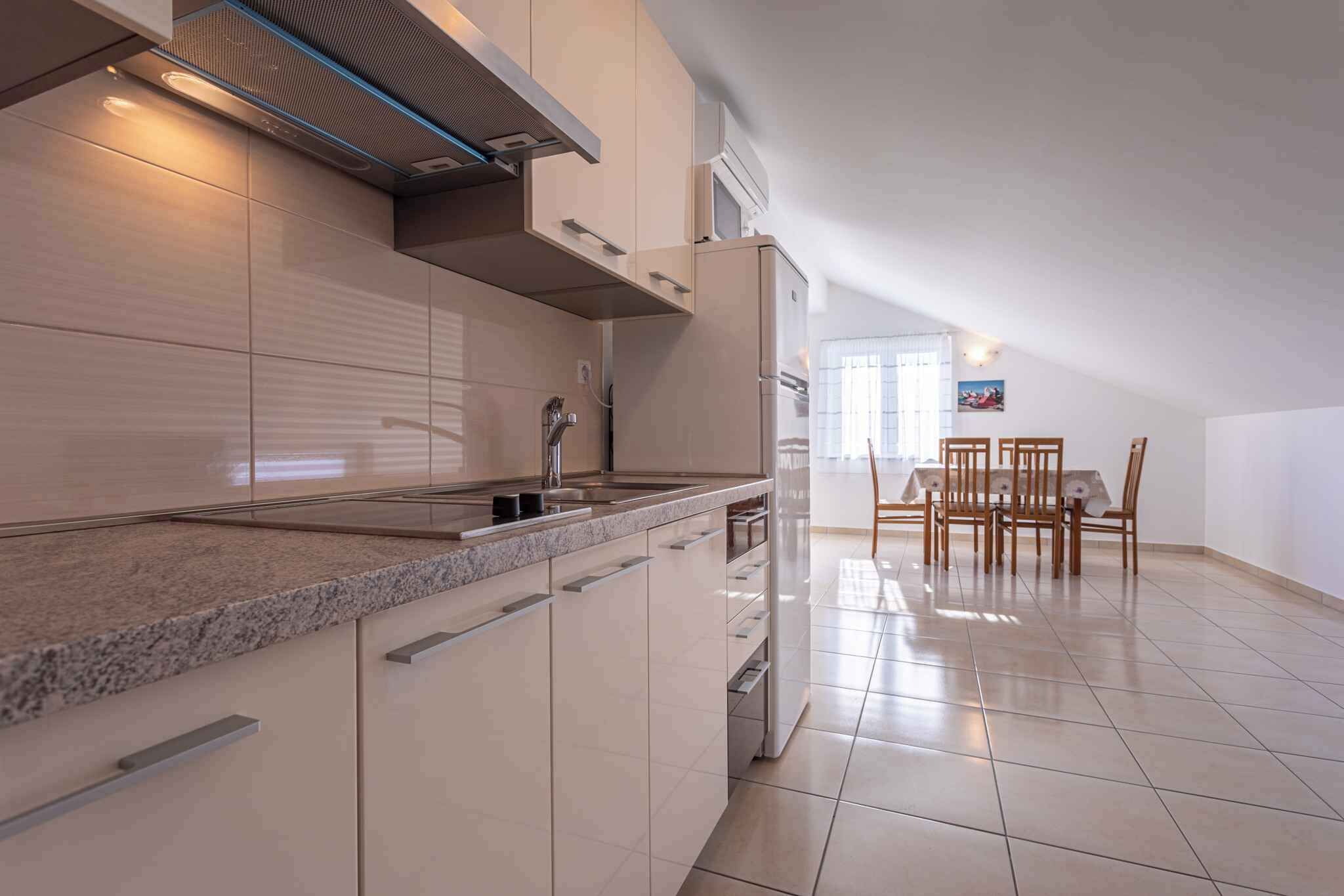 A modern kitchen with a granite countertop, stainless steel appliances, and a dining area with wooden chairs and a table.
